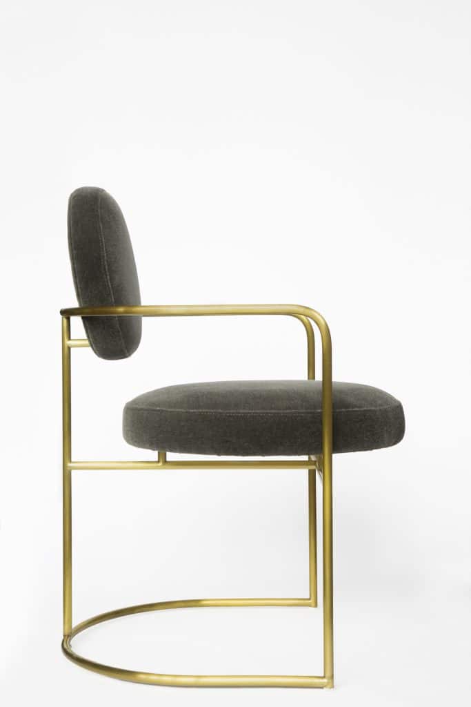 A studio product shot of a grey chair with gold hardware on a white background.